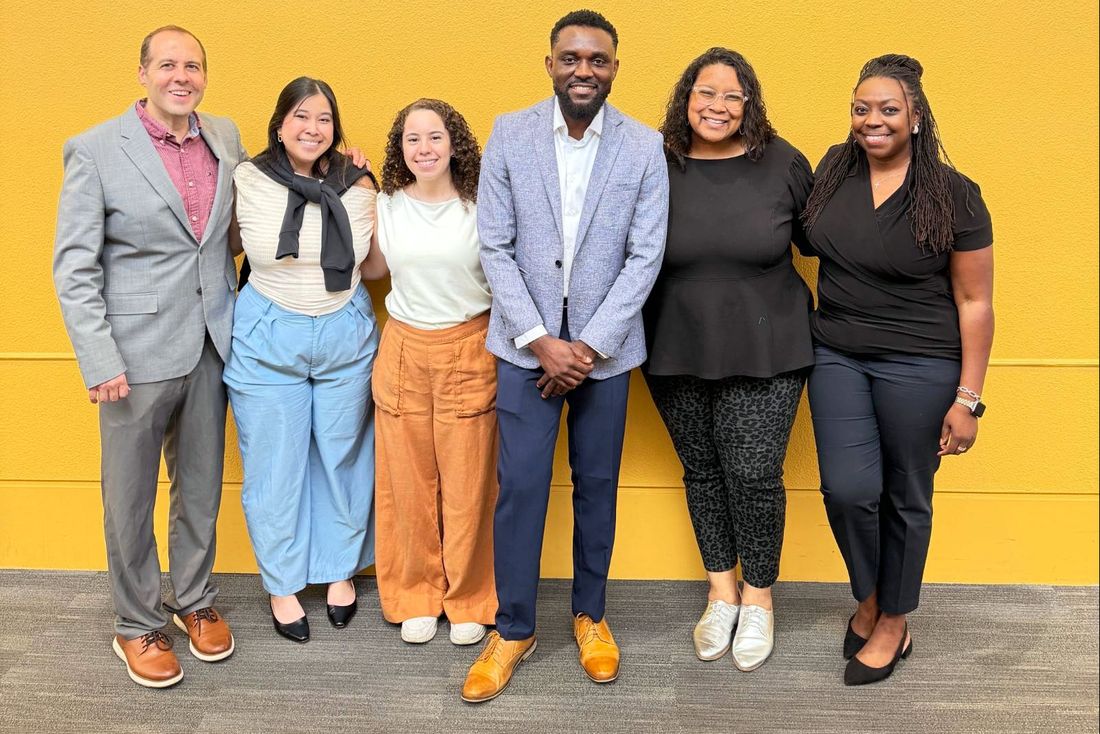Brittany Davis Morris with fellow marketing professionals in front of a yellow wall