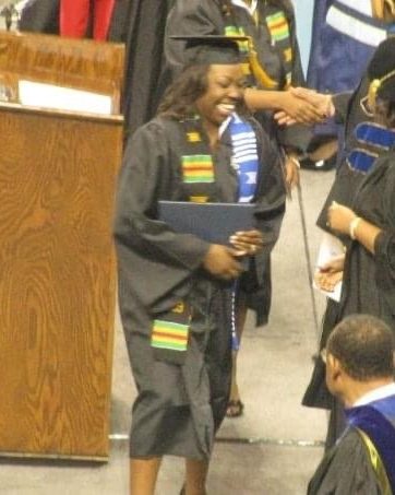 Brittany Davis Morris smiling as she receives her diploma at commencement