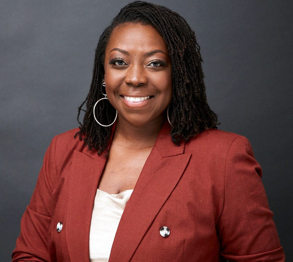 Brittany Davis Morris in a rust blazer, smiling